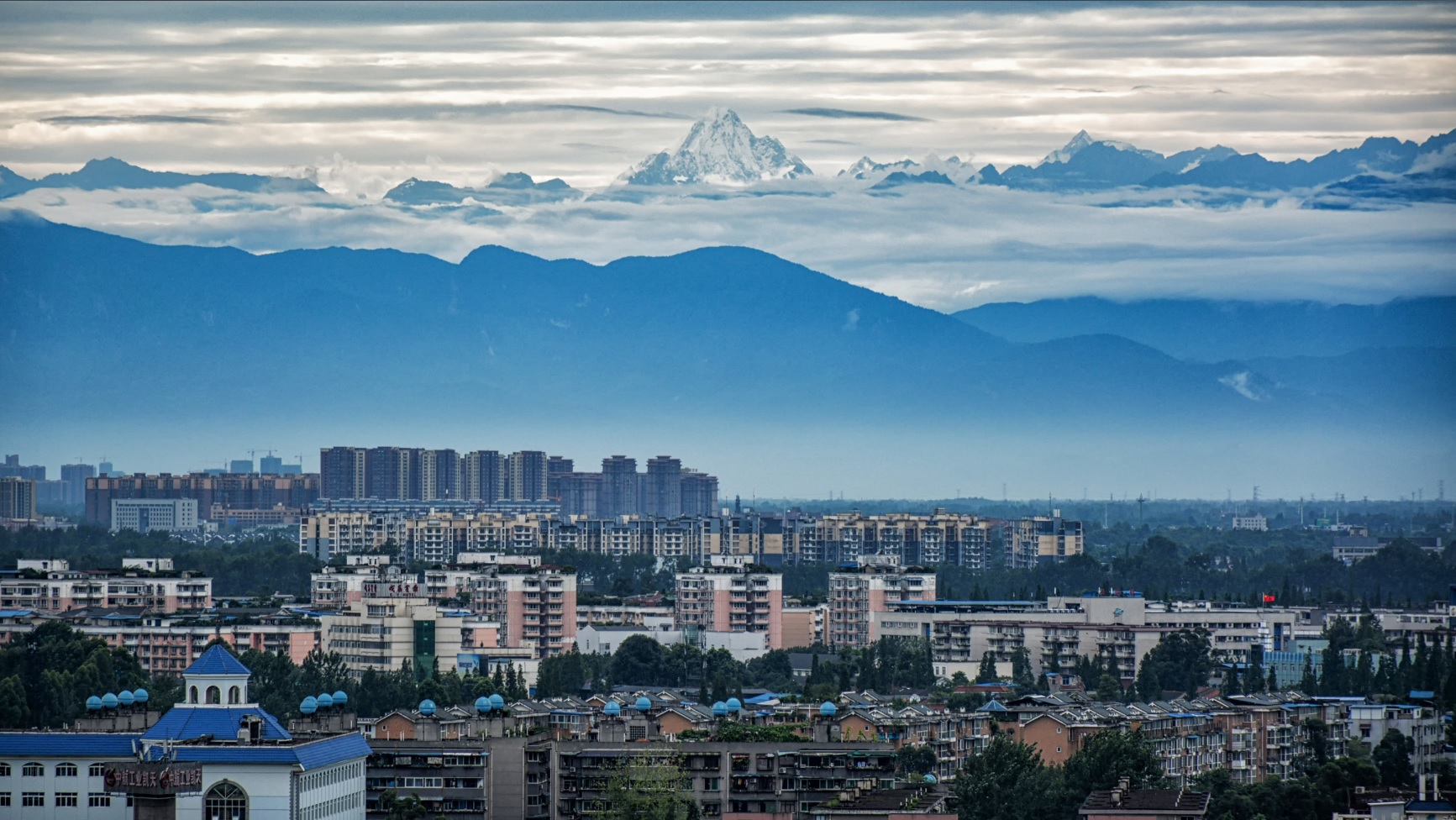 成都の市街地越しに遠望する四姑娘山